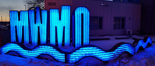The lighted MWMO sign sculpture at night.