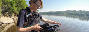 An MWMO staff member testing water quality in the river.