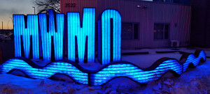The lighted MWMO sign sculpture at night