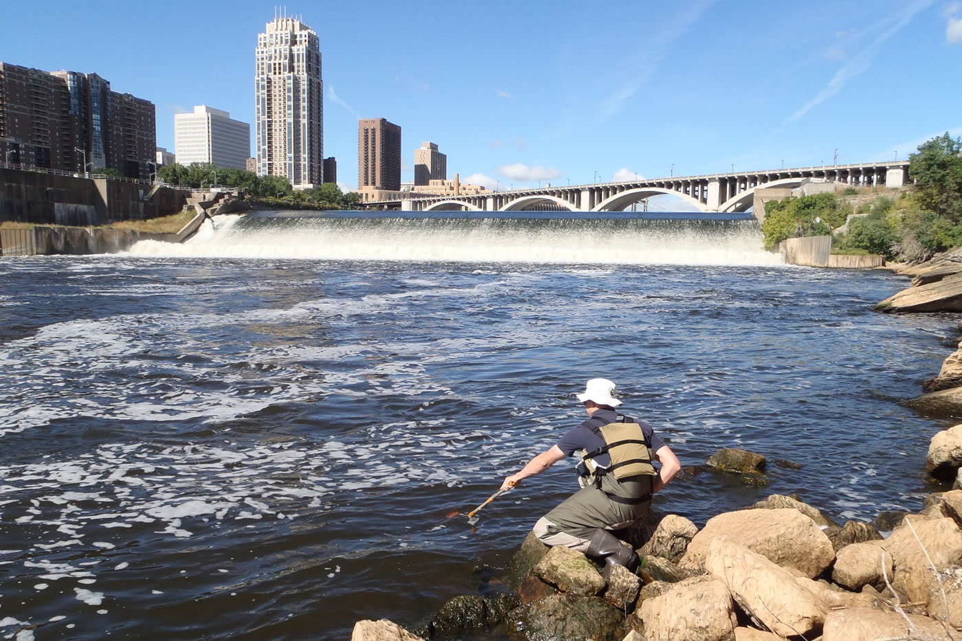 MWMO Environmental Specialist Brian Jastram collects a water sample near the University of Minnesota's St. Anthony Falls Laboratory.