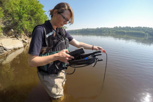 MWMO Intern Brittany Faust uses a multi-parameter water quality meter to test the water temperature, pH level, dissolved oxygen, conductivity and other factors in June 2015.