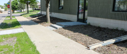 A "before" shot showing downspouts pointed at the sidewalk.