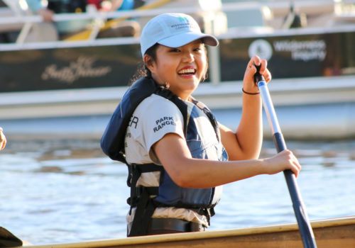 A park ranger leading a group of paddlers on a canoe on the Mississippi River.