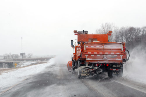 A snow plow applying road salt.