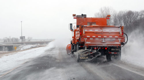 A snow plow applying road salt.