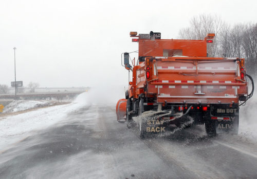 A snow plow applying road salt.
