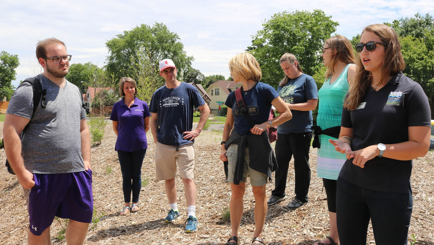 MWMO Youth and Community Outreach Specialist Michaela Neu, right, leads University of St. Thomas students on a tour of the raingarden, 