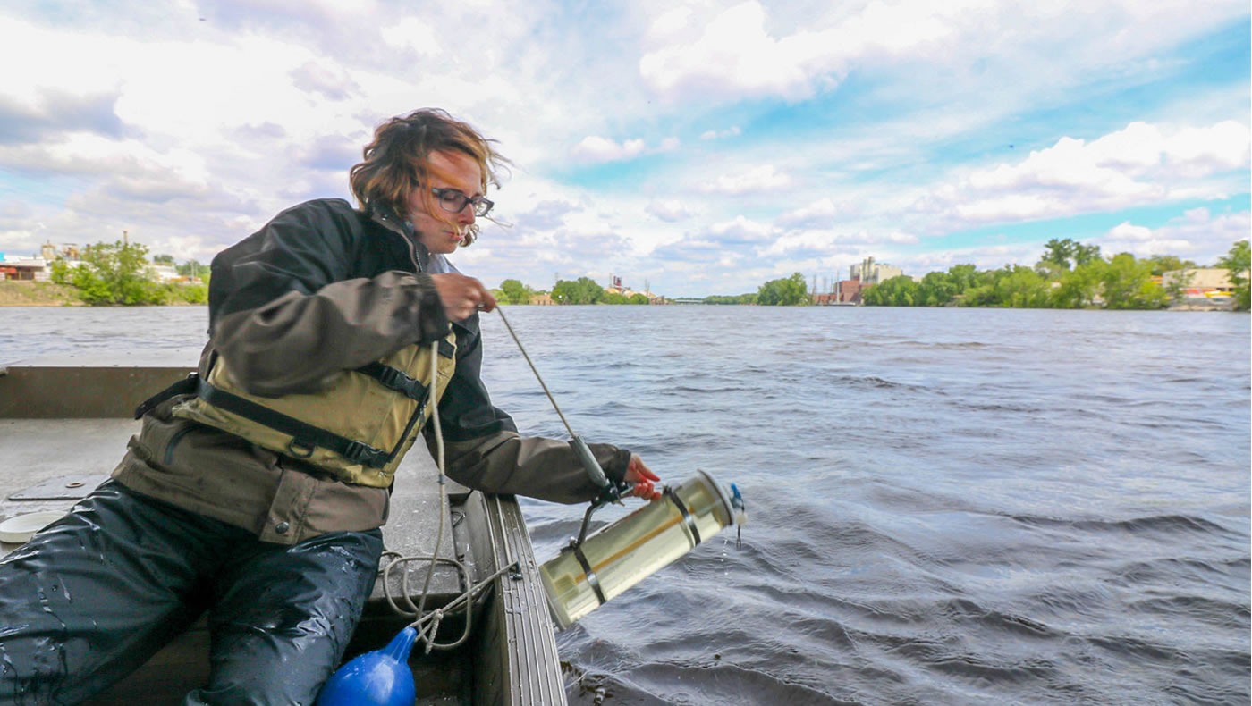 Monitoring team member lowers the Van Dorn water sampler into the Mississippi River.