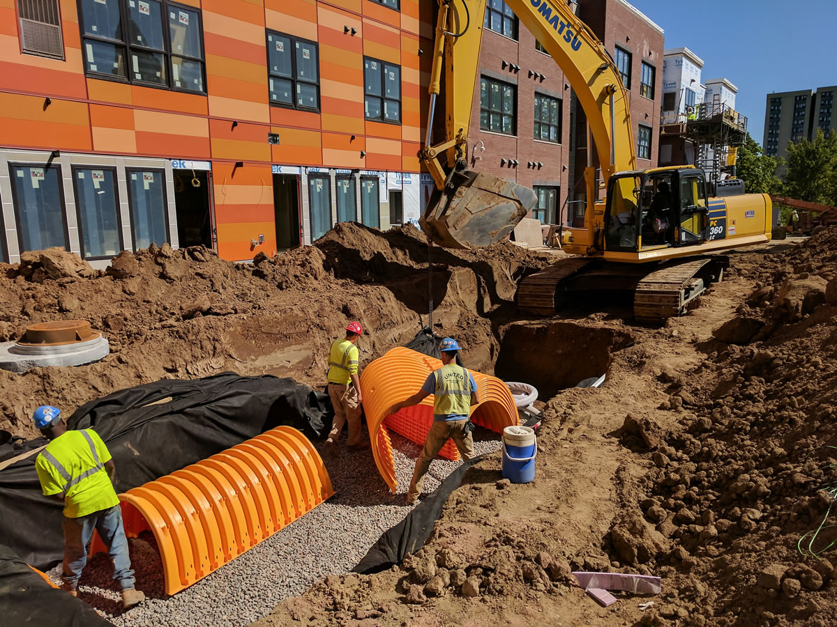 Workers install a filtration system next to the stormwater storage tank (buried) at EcoVillage Apartments.