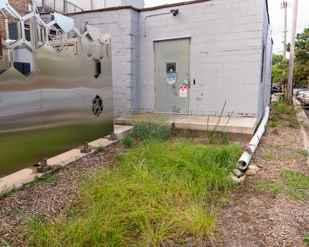 A downspout extension points toward a rain garden at PhyGen Coatings.