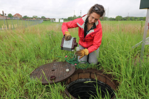 An MWMO intern collects a grab sample from a stormpipe in the 11CHF pipeshed.