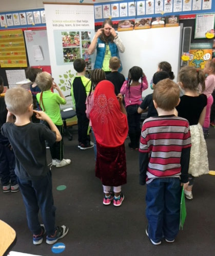 An educator stands before a group of young students.
