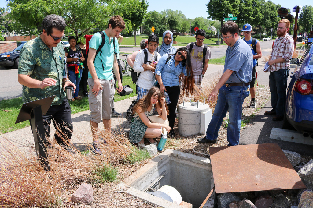 Engineers from Stantec shows a class of IB biology students how the tree trench receives runoff in the Edison High School parking lot.