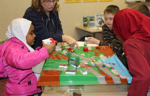 Children use a simulated watershed to learn how stormwater runoff carries pollution into waterways.