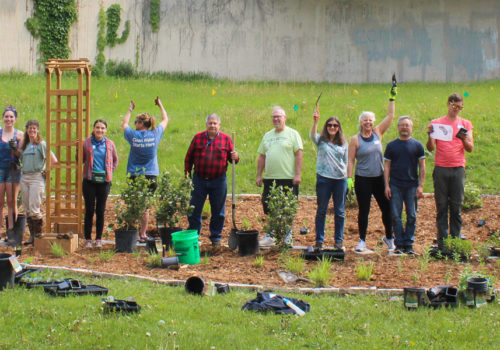 Raingarden planting volunteers raising their arms in celebration.