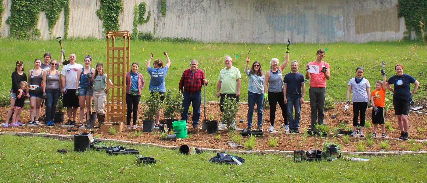 Raingarden planting volunteers raising their arms in celebration.