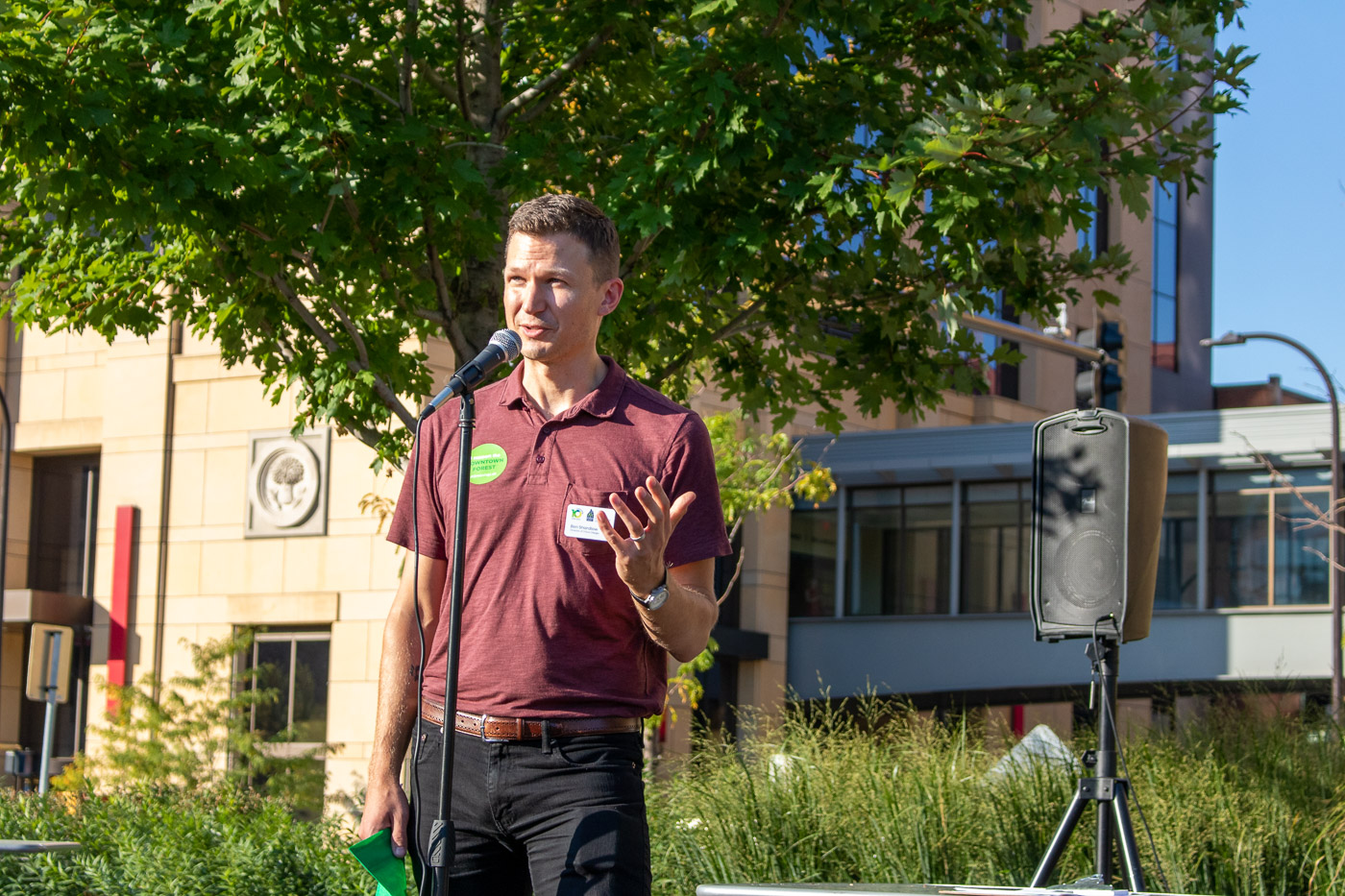 Ben Shardlow speaking in front of a microphone outdoors at an event.
