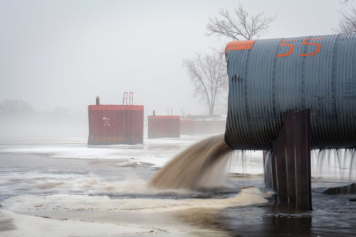 Stormwater gushes from an outfall on the Mississippi River in late winter.