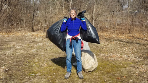 Woman holding bags of collected trash.