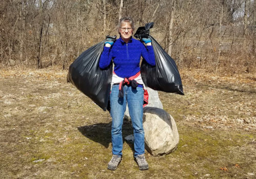 Woman holding bags of collected trash.