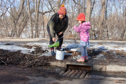 A woman and child clearing debris out of a stormdrain.