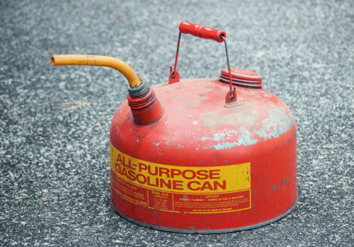 A gasoline can resting on pavement.