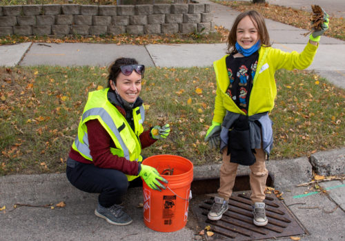 A smiling woman and child after cleaning a stormdrain.