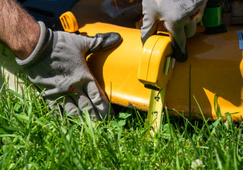 Measuring the height of a lawn mower deck with a tape measure.