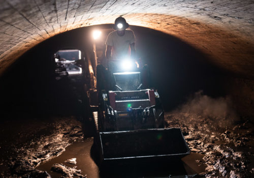 A worker drives a skidloader in the Old Bassett Creek Tunnel.