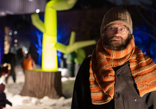 Artist Aaron Dysart stands in front of his lighted tree sculpture, Regrowth.