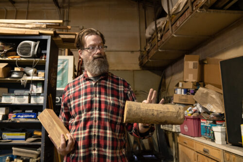 Aaron Dysart holds pieces of wood in his art studio.