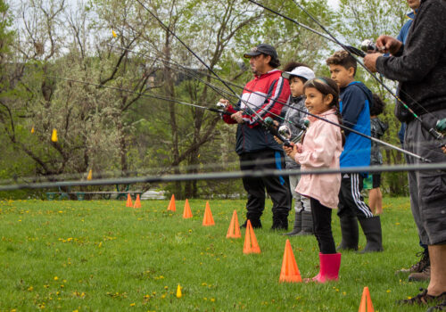 Children and adults practicing their casting technique at a learn-to-fish event.