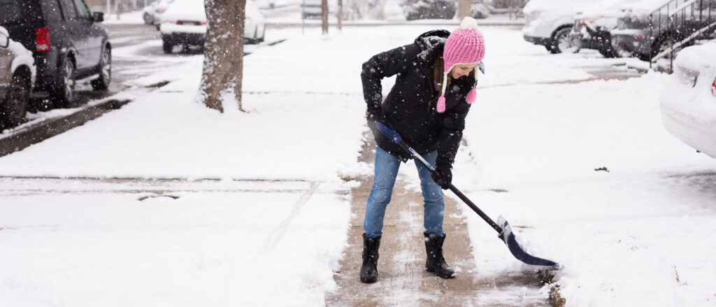 Woman in cute pink hat shoveling snow.