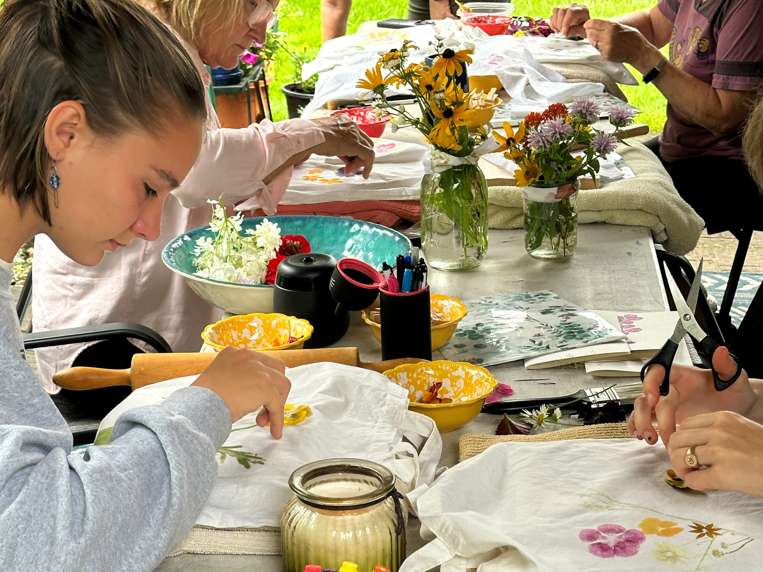 Community members flower pounding natural pigment onto fabric at a workshop