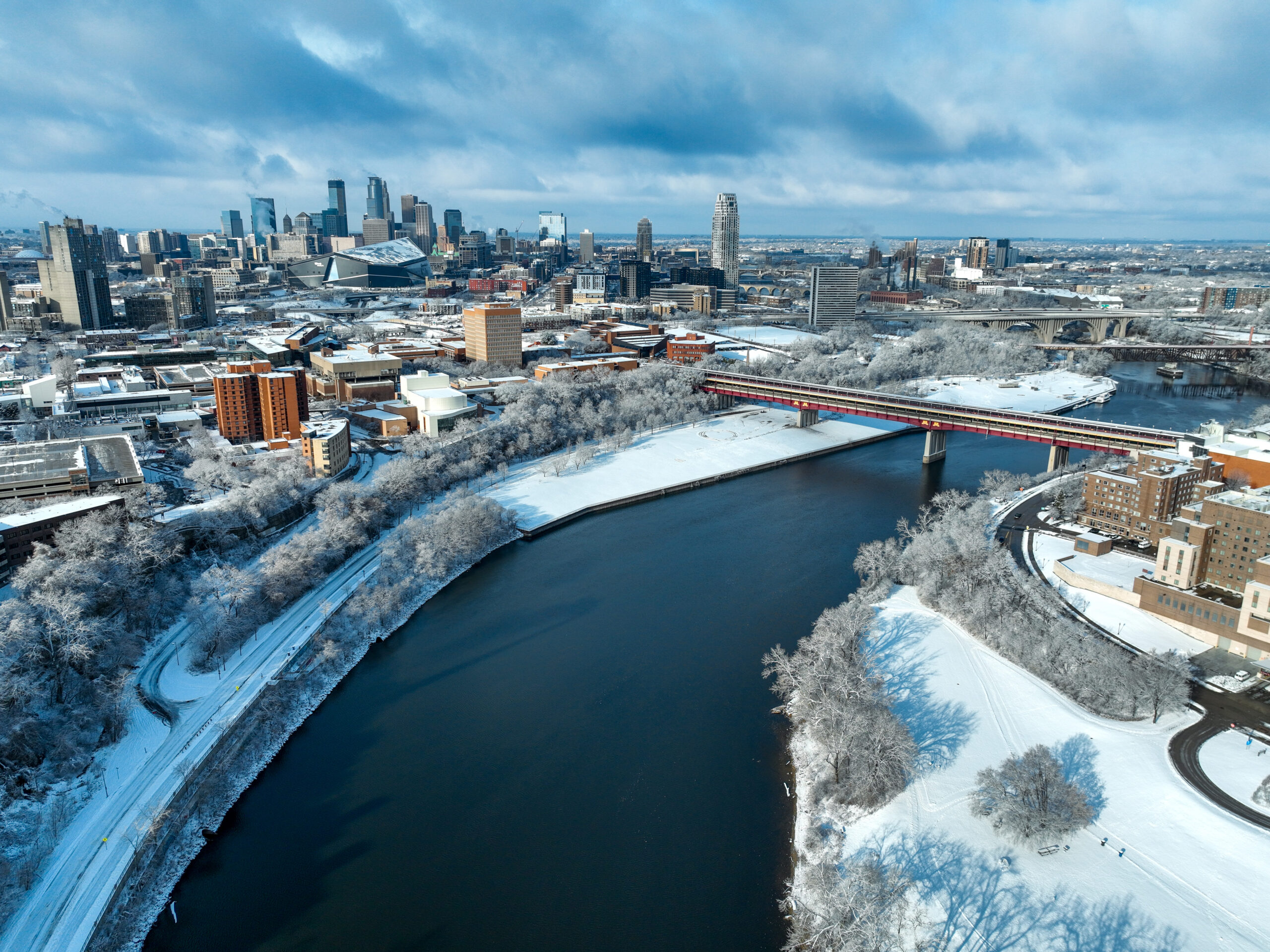 Downtown Minneapolis Winter Aerial of the Mississippi River at the Washington Bridge with the Minneapolis city skyline in the background.